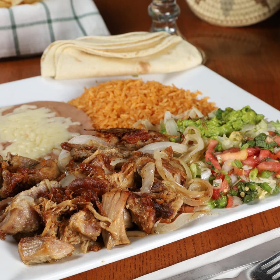 La Fuente Mexican Bar & Grill's carnitas plate with rice, beans, guacamole, pico de gallo, and tortillas.