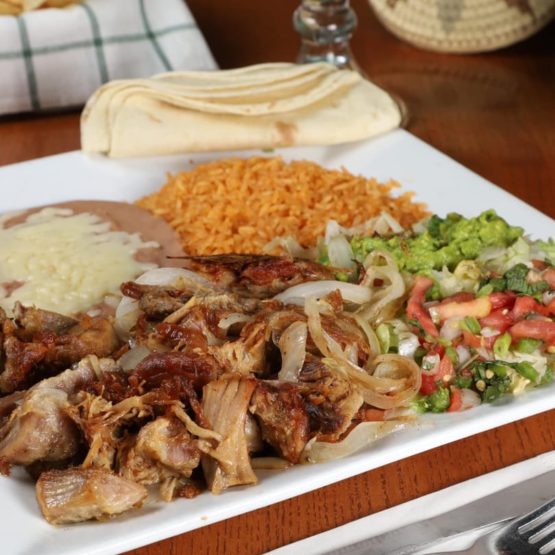 La Fuente Mexican Bar & Grill's carnitas plate with rice, beans, guacamole, pico de gallo, and tortillas.