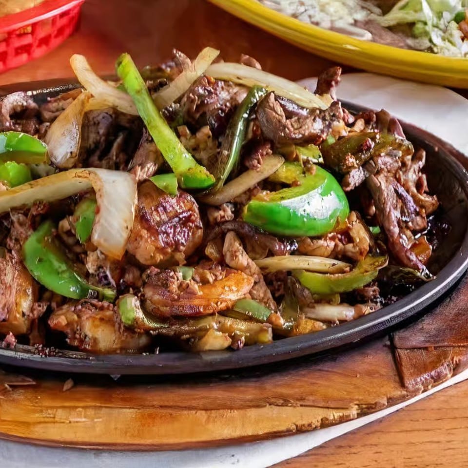 Sizzling La Fuente Mexican Bar & Grill fajitas with steak, onions, and green bell peppers.