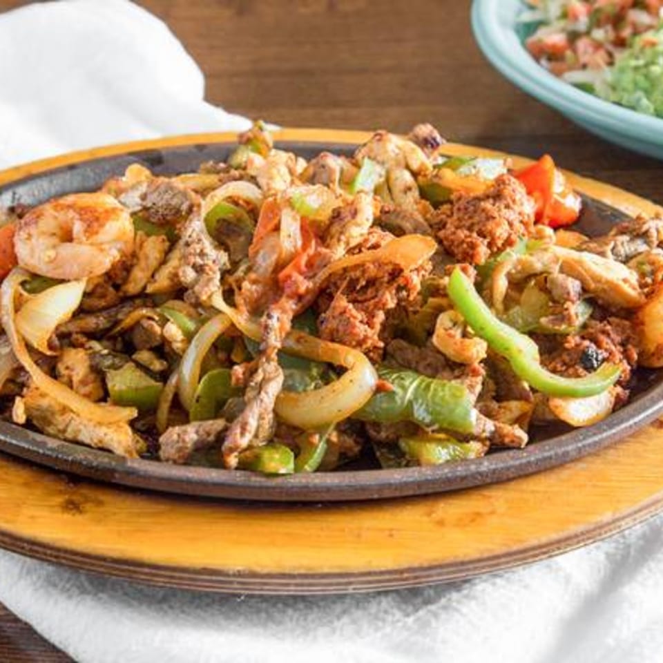 Sizzling La Fuente Mexican Bar & Grill fajitas with shrimp, beef, onions, and green peppers.